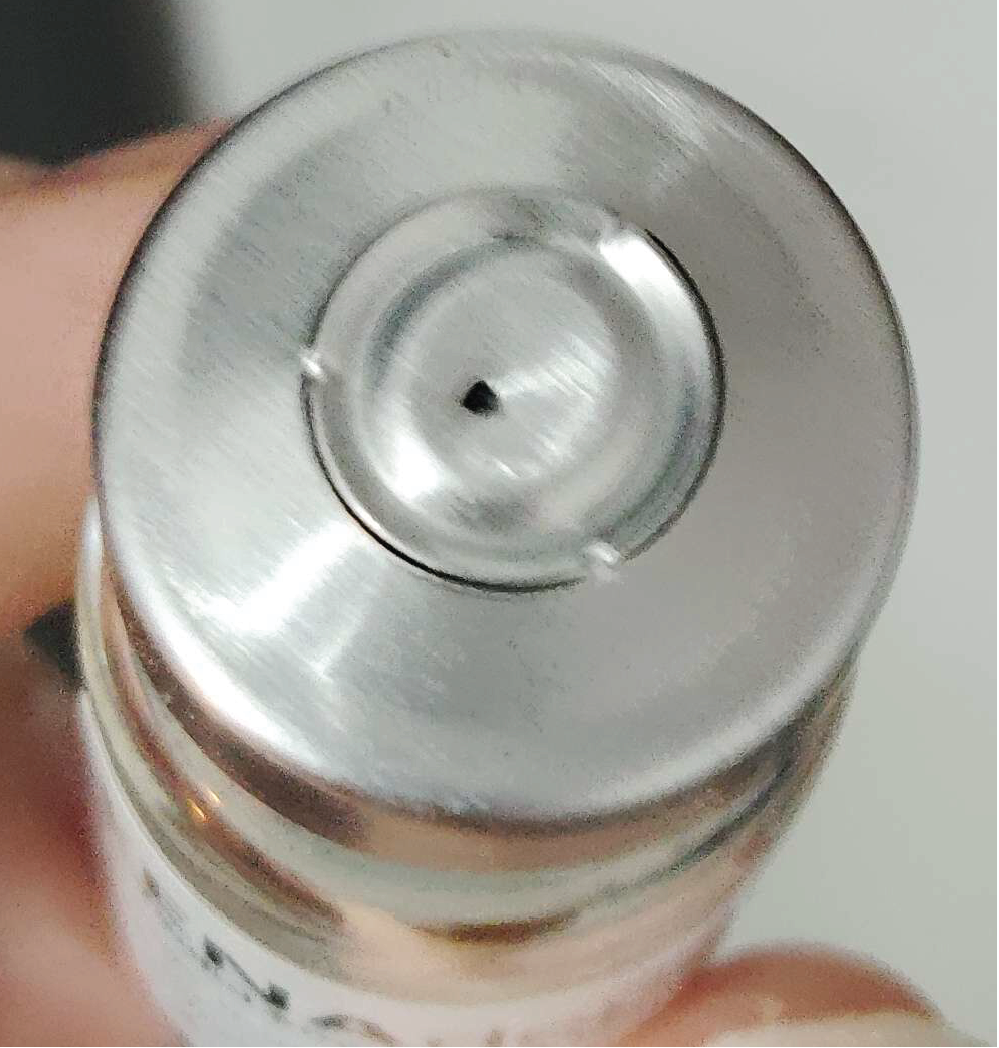 Picture of unopened vial stopper with a needle puncture through the metal cap, with a large red X mark superimposed in the corner.